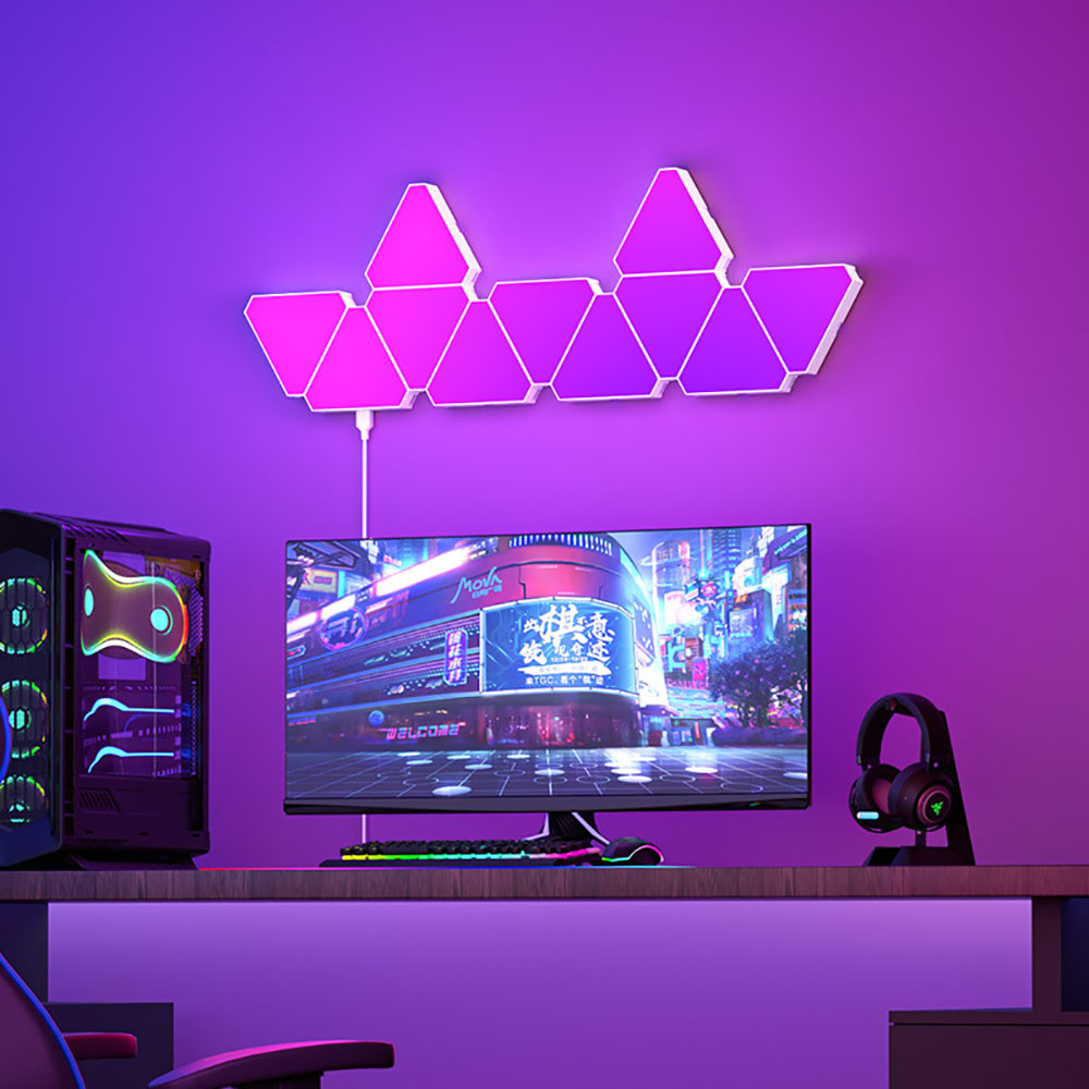 Painéis triangulares LED RGB em parede de setup gaming com iluminação rosa.